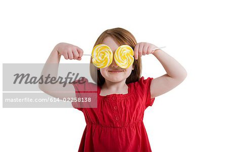 A girl covering her eyes with lollipops