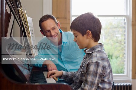 Father teaching son how to play the piano