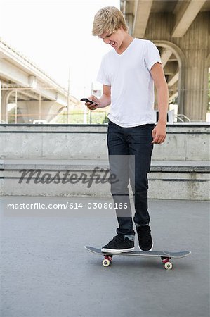 Teenage boy on skateboard with cellphone