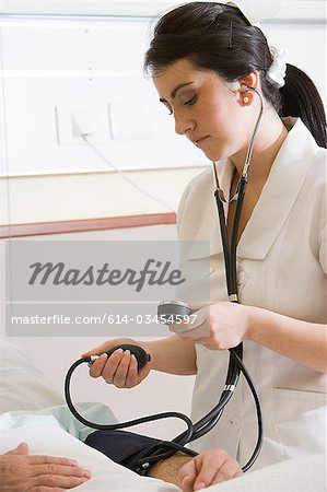 Nurse using blood pressure gauge on patient