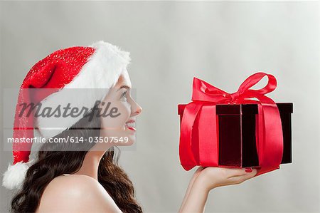 Young brunette woman wearing Santa hat with Christmas present