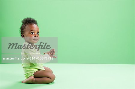 Baby boy kneeling against green background