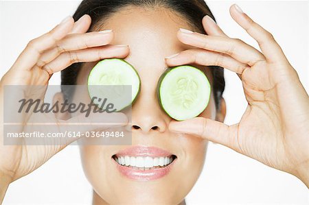 Woman holding cucumber over eyes