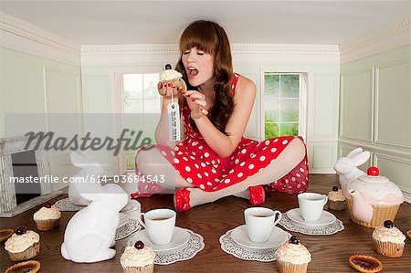 Young woman eating cake at tea party in small room