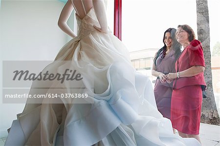 Mother and daughter looking at wedding dress in shop window