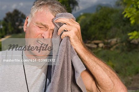 Senior man wiping face with towel after workout