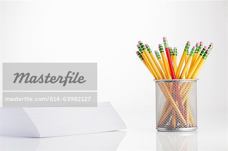 Pencils in pot and stack of paper