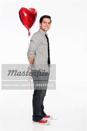 Young man holding balloon against white background