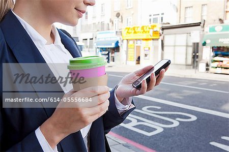 Close of businesswoman on street with coffee and smart phone