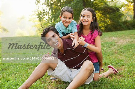 Father sitting with children in park, portrait