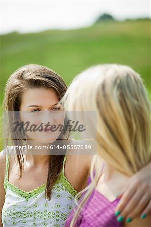 Young lesbian couple looking at each other intimately while sitting in the countryside