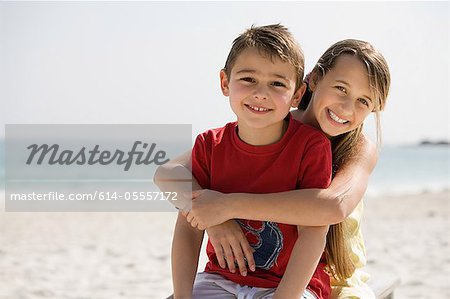 Brother and sister embracing on a beach