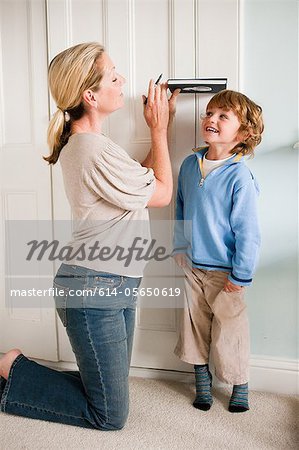 Mother measuring her son against a door with a book