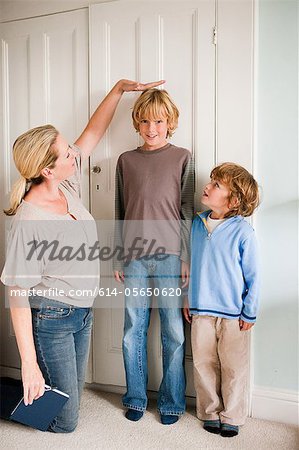 Mother measuring her sons at home