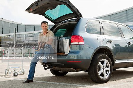 Man sitting on cart in airport carpark