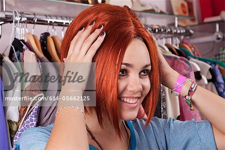 Young woman trying on wig in clothes shop, smiling