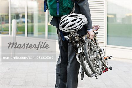 Mid adult businessman carrying folding bicycle