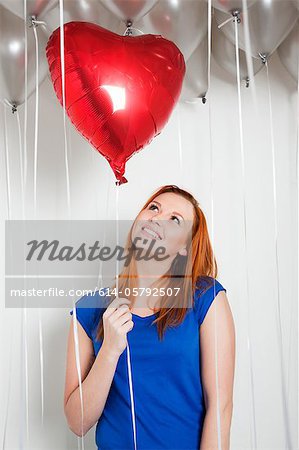 Young woman holding a heart shaped balloon