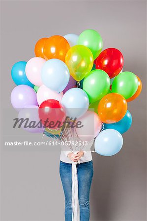 Woman holding large amount of balloons