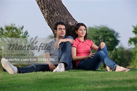 Couple sitting together next to a tree