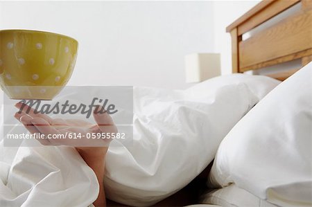Person under duvet being handed a coffee Person under duvet being handed a coffee