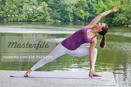 Mid adult woman performing yoga by river