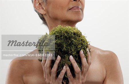 Senior woman holding plant, studio shot