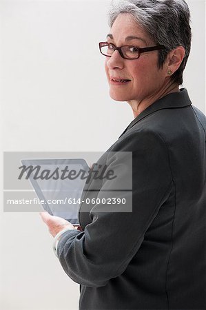 Mature businesswoman using digital tablet, studio shot