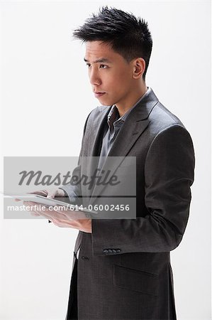 Young Asian businessman holding digital tablet, studio shot