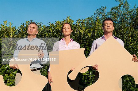Three businesspeople holding shapes