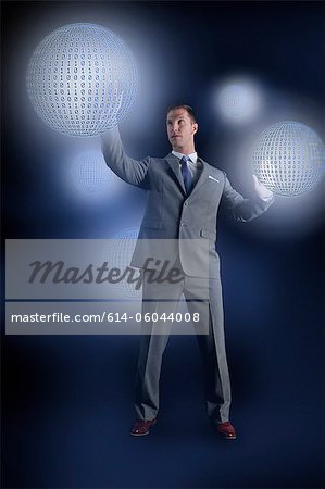 Businessman interacting with holographic binary globes Businessman interacting with holographic binary globes