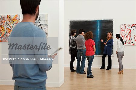 Men and women listening to guide in art gallery