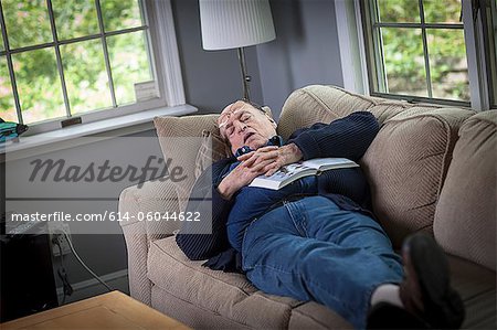 Senior man sleeping on sofa in living room
