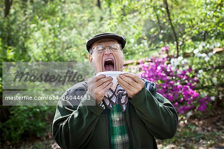 Senior man about to sneeze outdoors