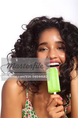 Young woman eating green popsicle, portrait