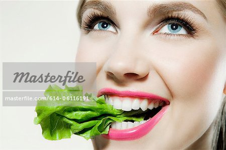 Young woman biting lettuce