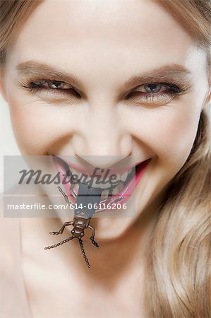 Young woman biting plastic beetle