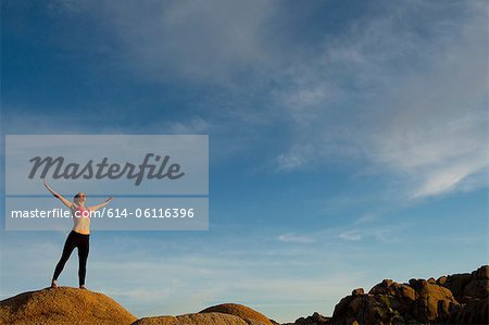 Young woman standing in desert with arms open