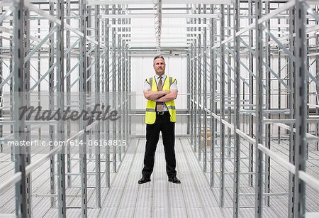 Man with arms folded in empty warehouse, portrait