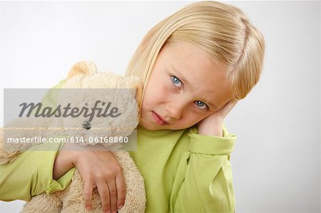 Girl with teddy covering ears