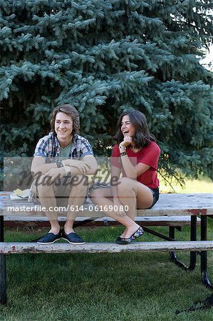 Teenage couple sitting on picnic table in park