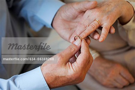 Senior man placing wedding ring on senior womans finger