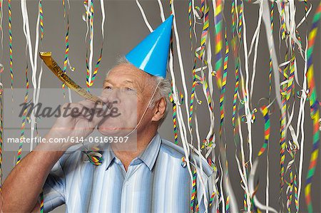 Senior man with party blower and streamers