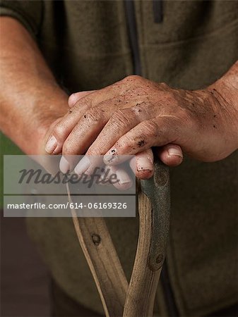 Man leaning with hands on wooden handle