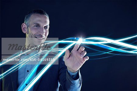 Businessman touching lines of light Businessman touching lines of light