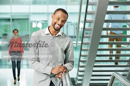 Young businessman by stairs in office