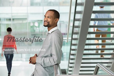 Young businessman by stairs in office