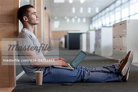 Man sitting on floor using laptop