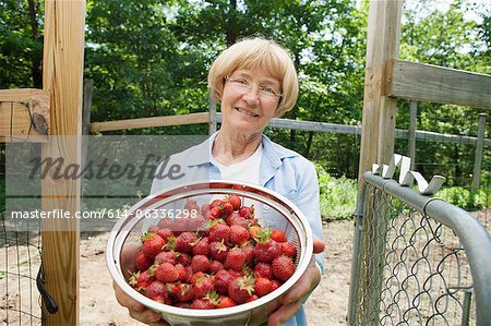 Woman holding colander with strawberries