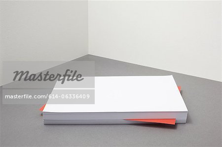 Red piece of paper amongst stack of blank paper Red piece of paper amongst stack of blank paper